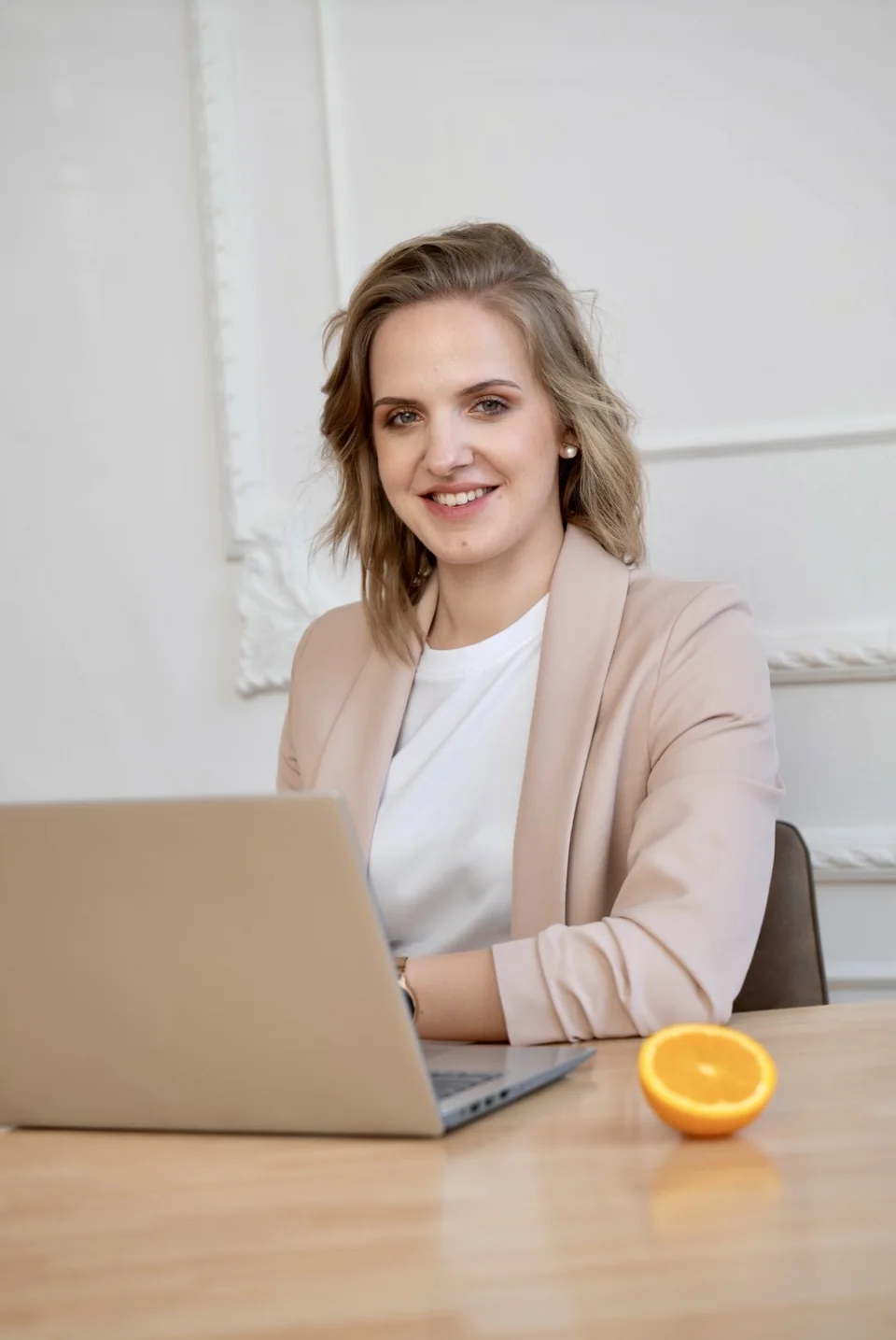Aleksandra Panasiuk uśmiecha się, siedząc przy laptopie w jasnym wnętrzu